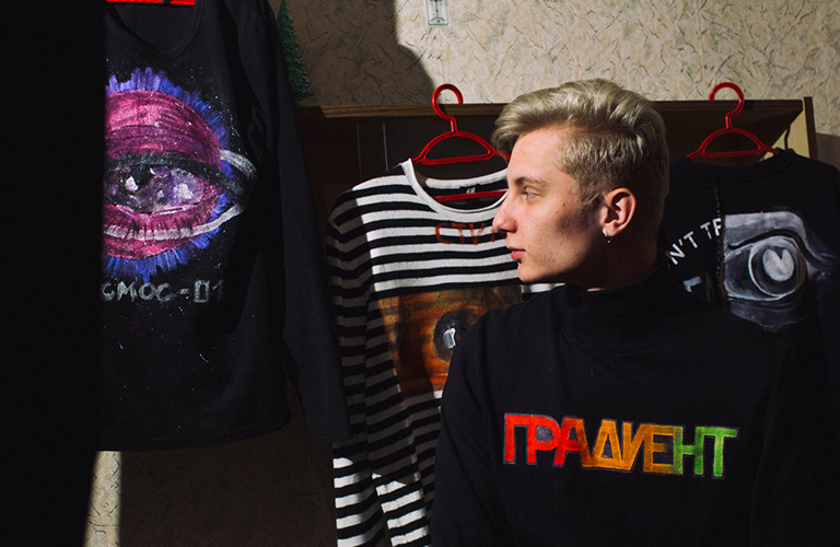 Молодой художник и его футболки с глазами на фоне ковра