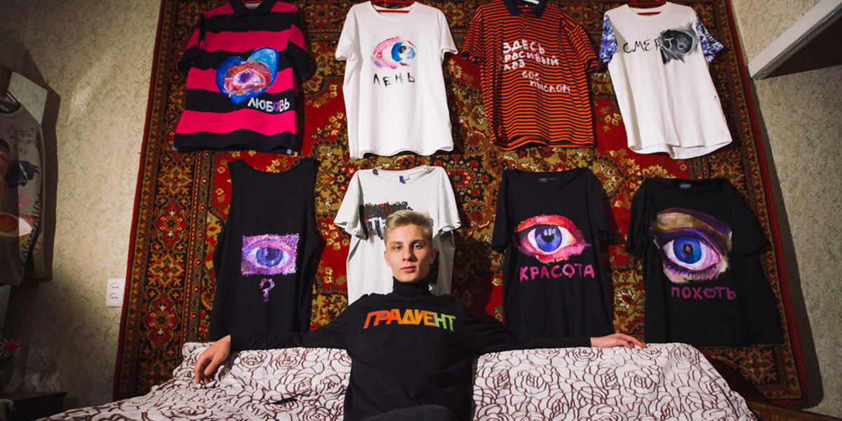 Молодой художник и его футболки с глазами на фоне ковра
