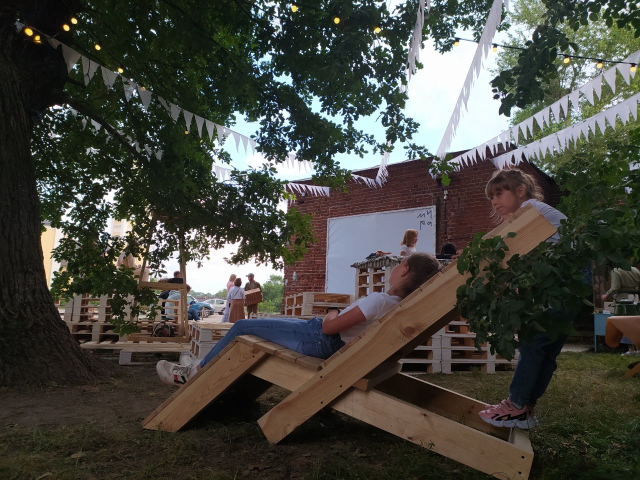 В Суздале появилось новое место для семейного отдыха. Маленькие жители города при поддержке команды энтузиастов сами разработали проект и создали дворик на Кремлевской улице! Теперь там устраивают открытые кинопоказы, пьют чай из самовара и наслаждаются летом под древним дубом.