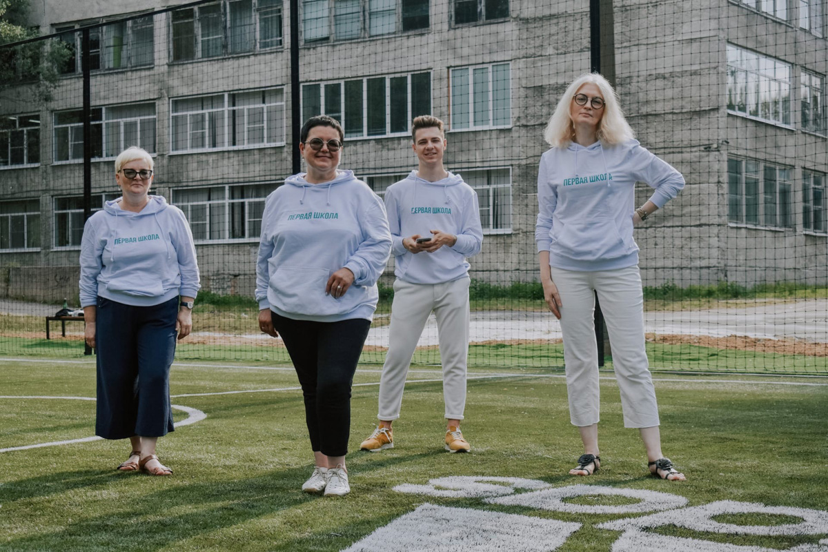 Узнаваемость Первой школы, рассказывает заместитель директора, сейчас базируется на целом спектре мерча - это блокноты для учителей и учеников, шопперы, футболки и худи, бутылки для воды, значки. А началось все с уникальной одежды, которая появилась раньше подаренного Юрием Дудем футбольного поля.